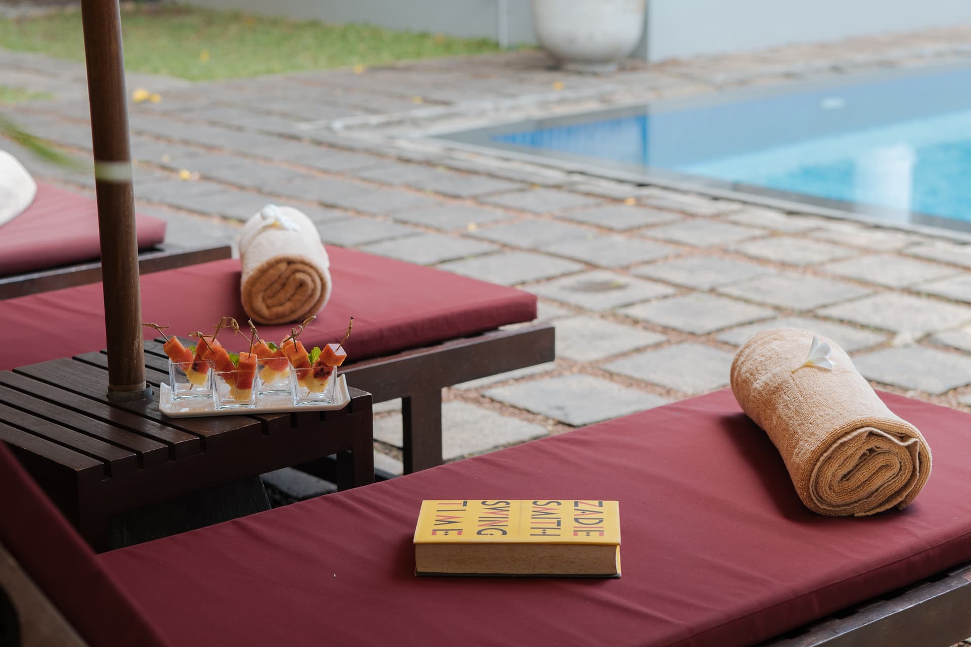 Lounging by the pool's edge with a fruit skewers and a book - unhurried hospitality.